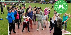 A group of people participating in a dance workshop outside in a park